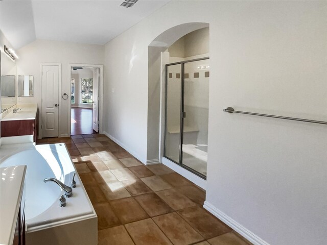 bathroom with tile patterned flooring, vanity, lofted ceiling, and plus walk in shower