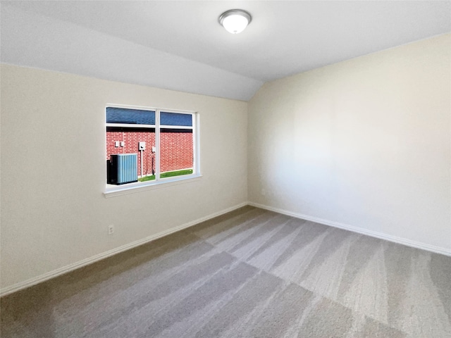 carpeted empty room with lofted ceiling