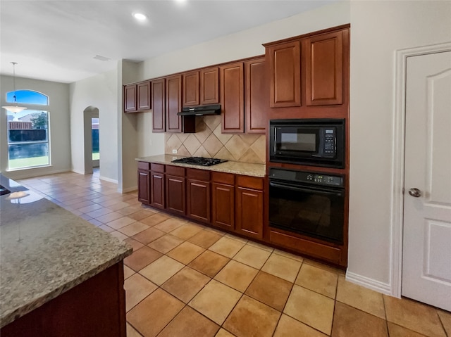 kitchen featuring tasteful backsplash, light stone counters, black appliances, pendant lighting, and light tile patterned flooring