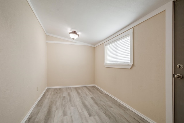 empty room with crown molding, light hardwood / wood-style floors, and lofted ceiling