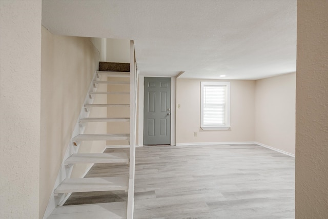 stairway featuring wood-type flooring and a textured ceiling