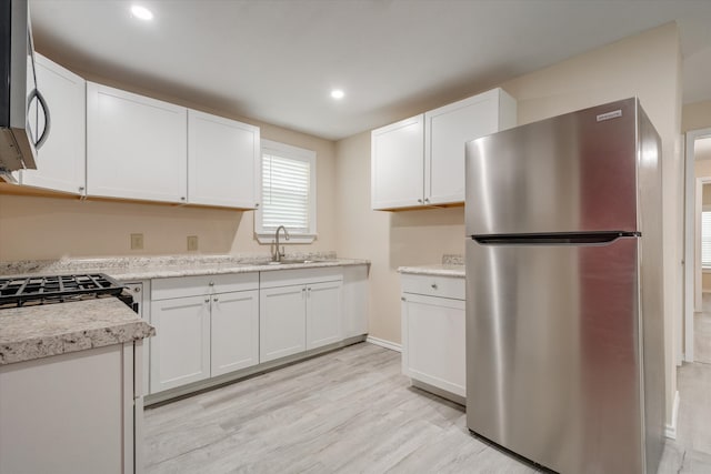 kitchen featuring white cabinets, appliances with stainless steel finishes, light wood-type flooring, and sink