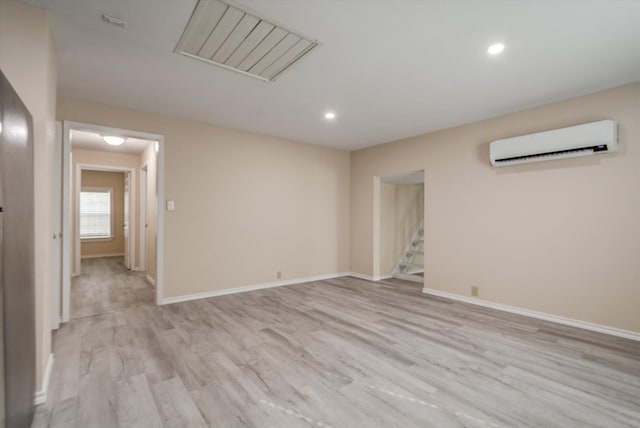 unfurnished room featuring light hardwood / wood-style floors and a wall unit AC