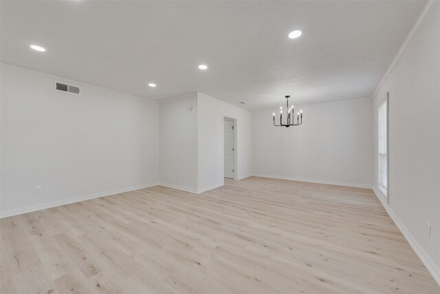 unfurnished room featuring crown molding, light hardwood / wood-style floors, and a notable chandelier