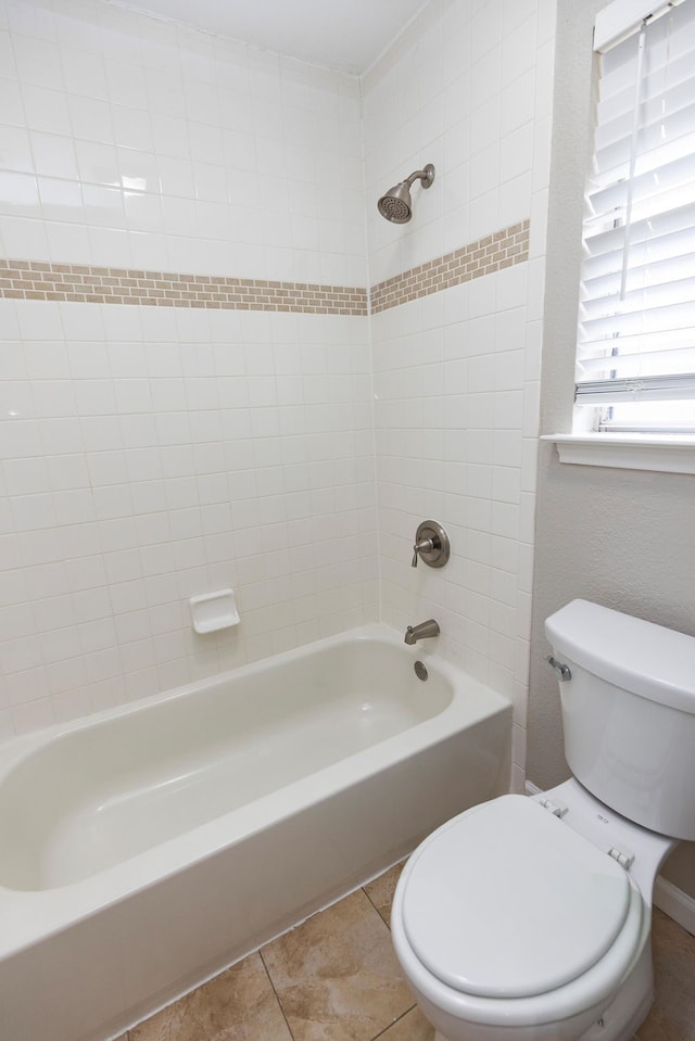 bathroom featuring tile patterned floors, toilet, and tiled shower / bath