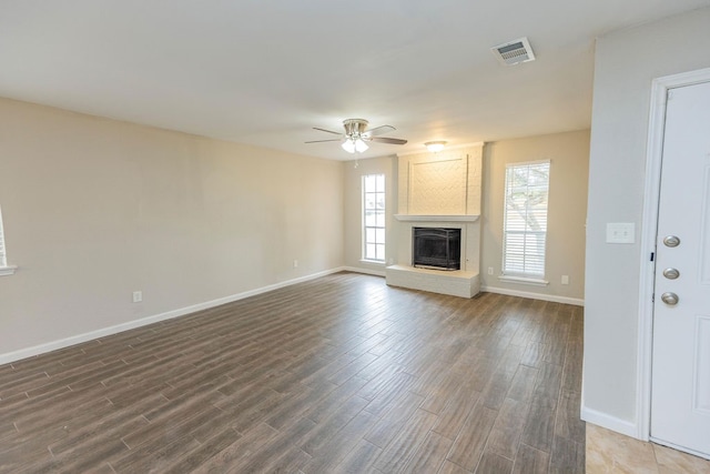 unfurnished living room featuring a fireplace, ceiling fan, and dark hardwood / wood-style flooring