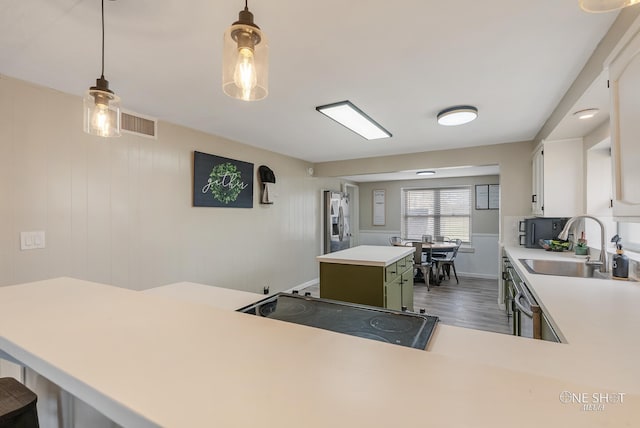 kitchen with a center island, sink, dark wood-type flooring, decorative light fixtures, and white cabinets