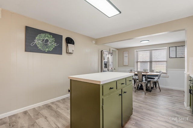 kitchen featuring stainless steel fridge, light hardwood / wood-style flooring, a kitchen island, and green cabinets