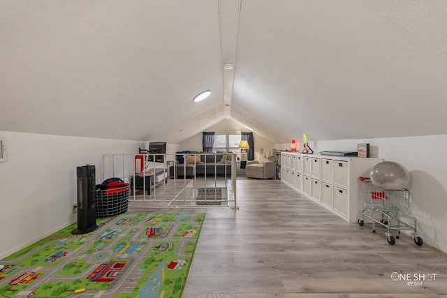 recreation room featuring light wood-type flooring and vaulted ceiling