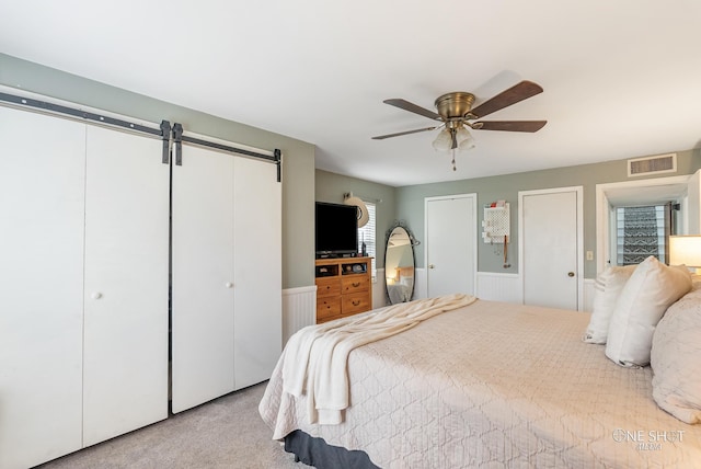 carpeted bedroom with a barn door and ceiling fan