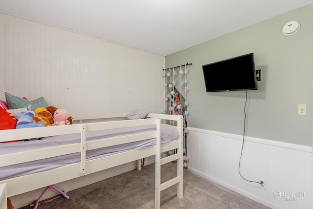 bedroom featuring light carpet and wooden walls