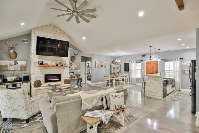 living room with a fireplace, vaulted ceiling, ceiling fan, and sink