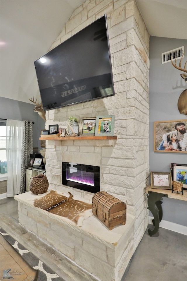 interior details featuring concrete flooring and a stone fireplace