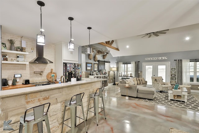 kitchen with a breakfast bar, black fridge, pendant lighting, ceiling fan, and decorative backsplash