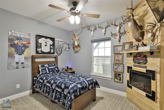 bedroom with ceiling fan, a large fireplace, and carpet