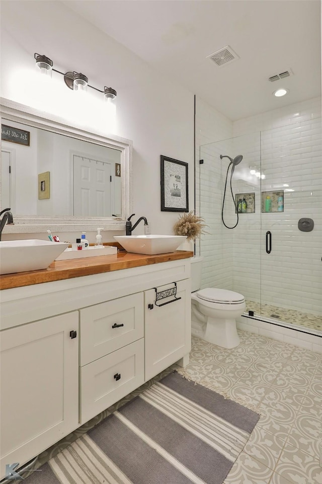 bathroom with vanity, toilet, and a shower with door