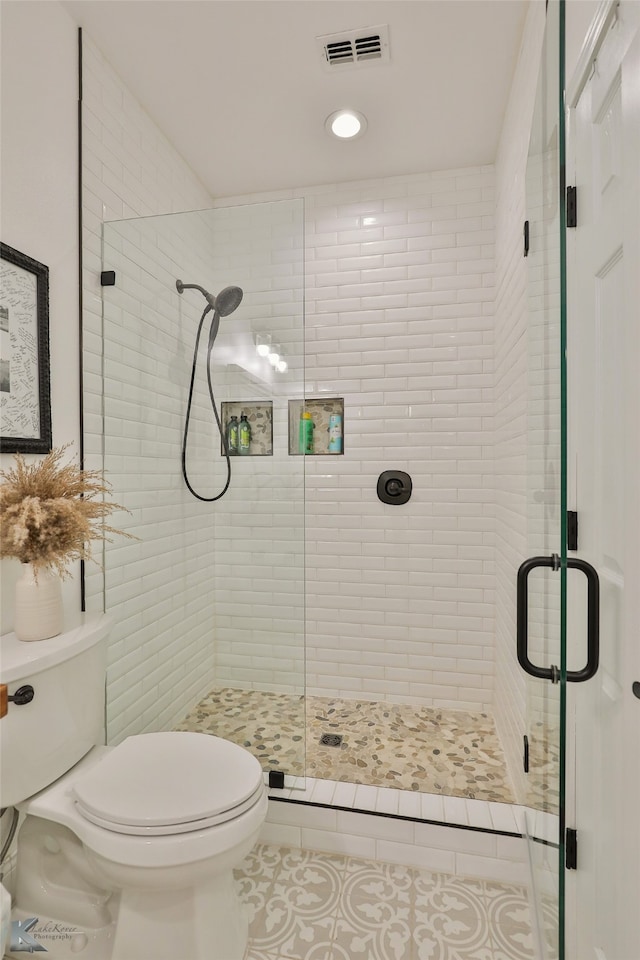 bathroom with tile patterned flooring, toilet, and an enclosed shower