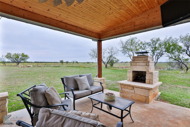 view of patio with an outdoor living space with a fireplace and a rural view