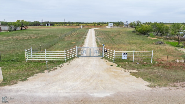 view of gate with a yard and a rural view