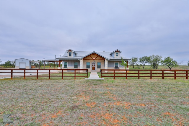 view of front facade with an outbuilding, a rural view, a front yard, a porch, and a garage