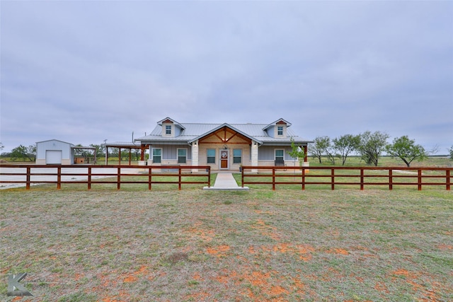 view of front of property with a rural view, a garage, a front lawn, and an outbuilding