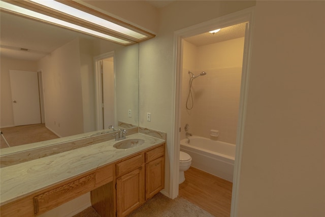 full bathroom with tiled shower / bath combo, vanity, hardwood / wood-style floors, and toilet