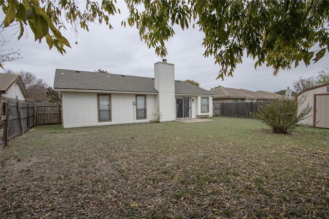 rear view of house featuring a lawn and a storage unit