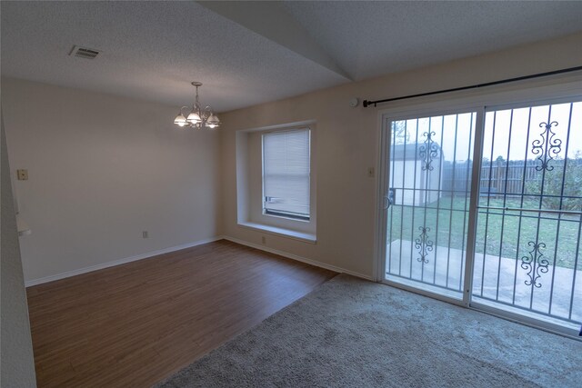 spare room with a textured ceiling, a notable chandelier, and hardwood / wood-style flooring