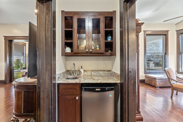 bar featuring dishwashing machine, wet bar, a sink, and wood finished floors