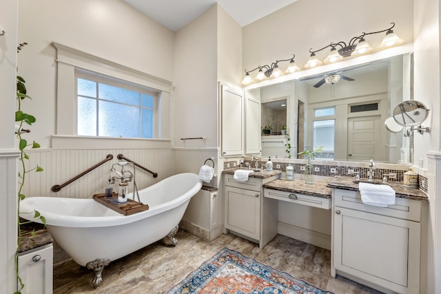 full bathroom with ceiling fan, vanity, a freestanding bath, and wainscoting