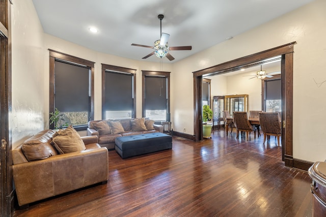 living area featuring plenty of natural light, hardwood / wood-style flooring, ceiling fan, and baseboards