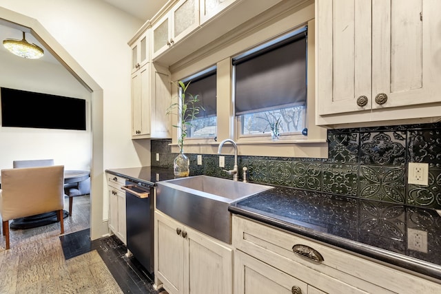 kitchen featuring a sink, dark wood-style floors, dishwasher, tasteful backsplash, and glass insert cabinets