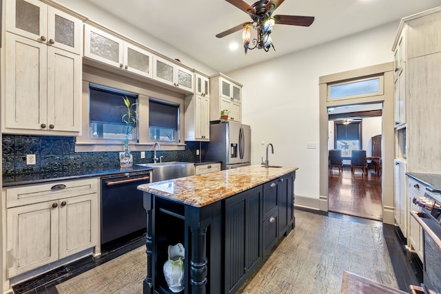 kitchen featuring black dishwasher, backsplash, a sink, an island with sink, and stainless steel fridge with ice dispenser