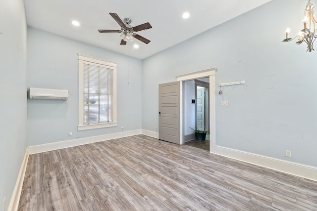 interior space featuring recessed lighting, ceiling fan with notable chandelier, wood finished floors, baseboards, and an AC wall unit