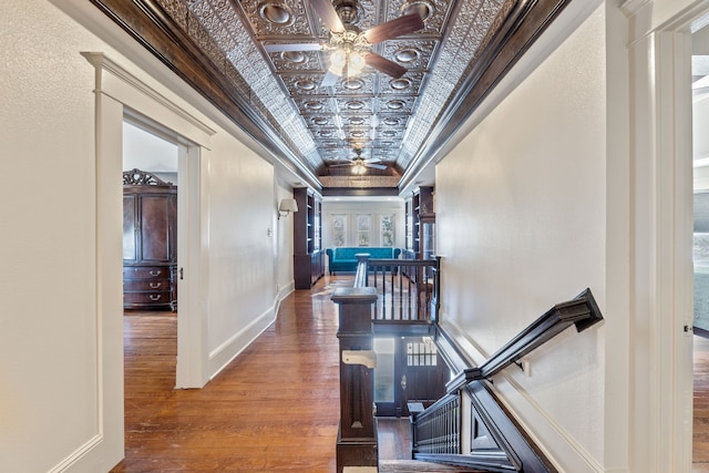 corridor with an upstairs landing, baseboards, hardwood / wood-style floors, an ornate ceiling, and crown molding