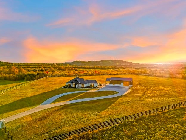 aerial view at dusk with a mountain view and a rural view