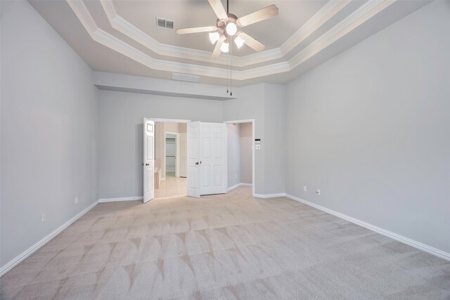 unfurnished room featuring ceiling fan, ornamental molding, light carpet, and a tray ceiling