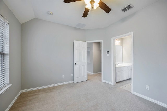 unfurnished bedroom featuring ceiling fan, light colored carpet, lofted ceiling, and ensuite bathroom