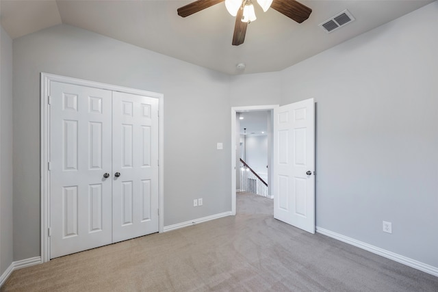 unfurnished bedroom featuring light carpet, a closet, lofted ceiling, and ceiling fan