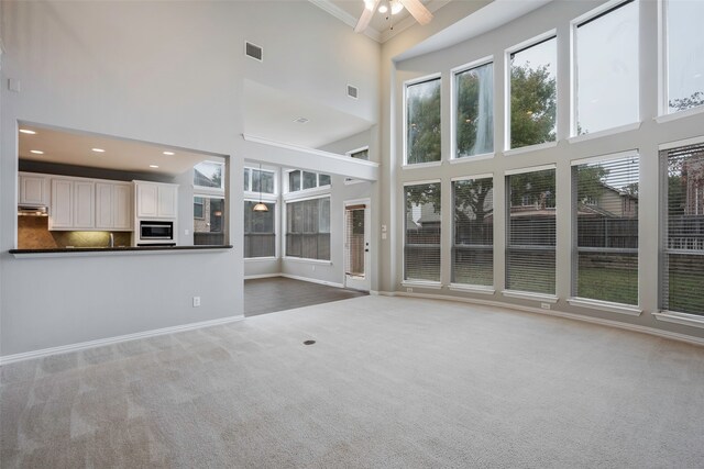 unfurnished living room featuring carpet flooring, a towering ceiling, and ornamental molding