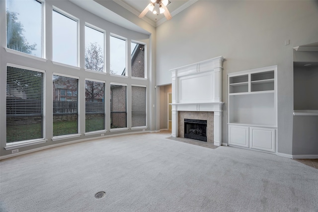 unfurnished living room featuring a towering ceiling, ornamental molding, and light carpet