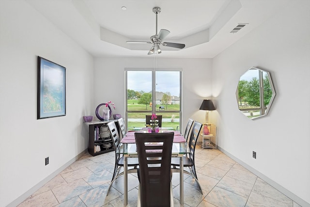 dining area featuring ceiling fan, a healthy amount of sunlight, and a raised ceiling