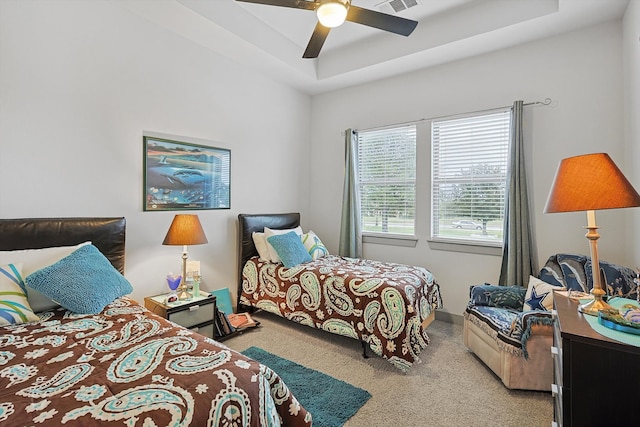 bedroom featuring ceiling fan, carpet floors, and a tray ceiling