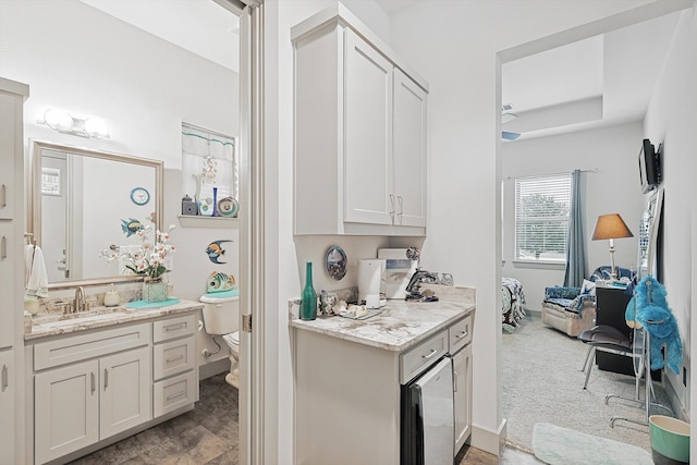 kitchen featuring white cabinetry, sink, light colored carpet, and light stone counters