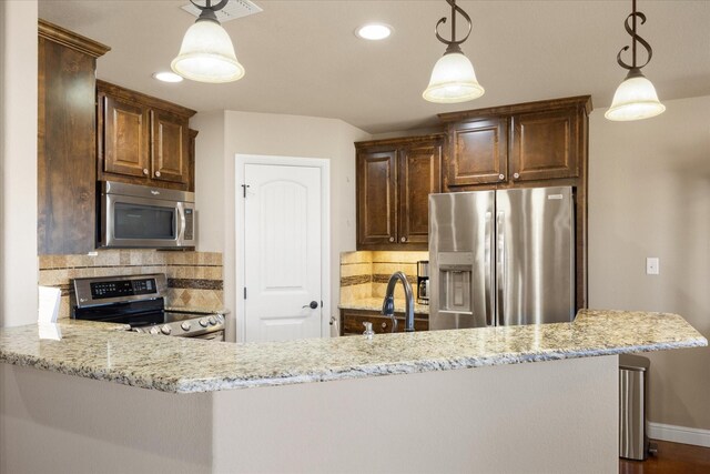 kitchen with light stone countertops, dark brown cabinetry, and stainless steel appliances