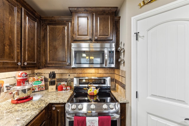 kitchen with dark brown cabinets, light stone countertops, and stainless steel appliances