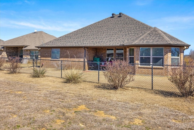 back of house with fence private yard, a shingled roof, and brick siding