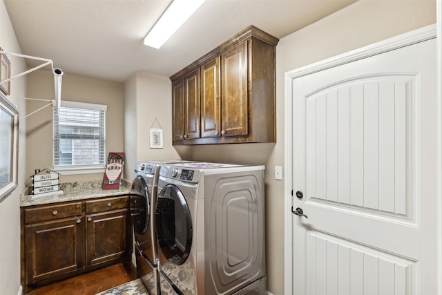 washroom featuring cabinets, a textured ceiling, and washer and dryer