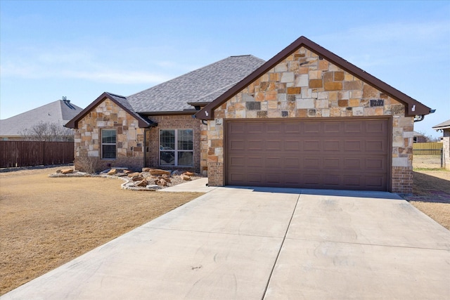 view of front of property featuring roof with shingles, fence, a garage, stone siding, and driveway