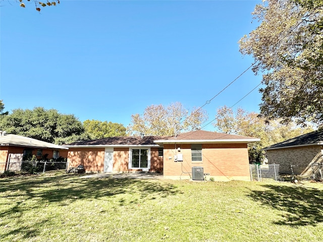 rear view of property with cooling unit and a lawn